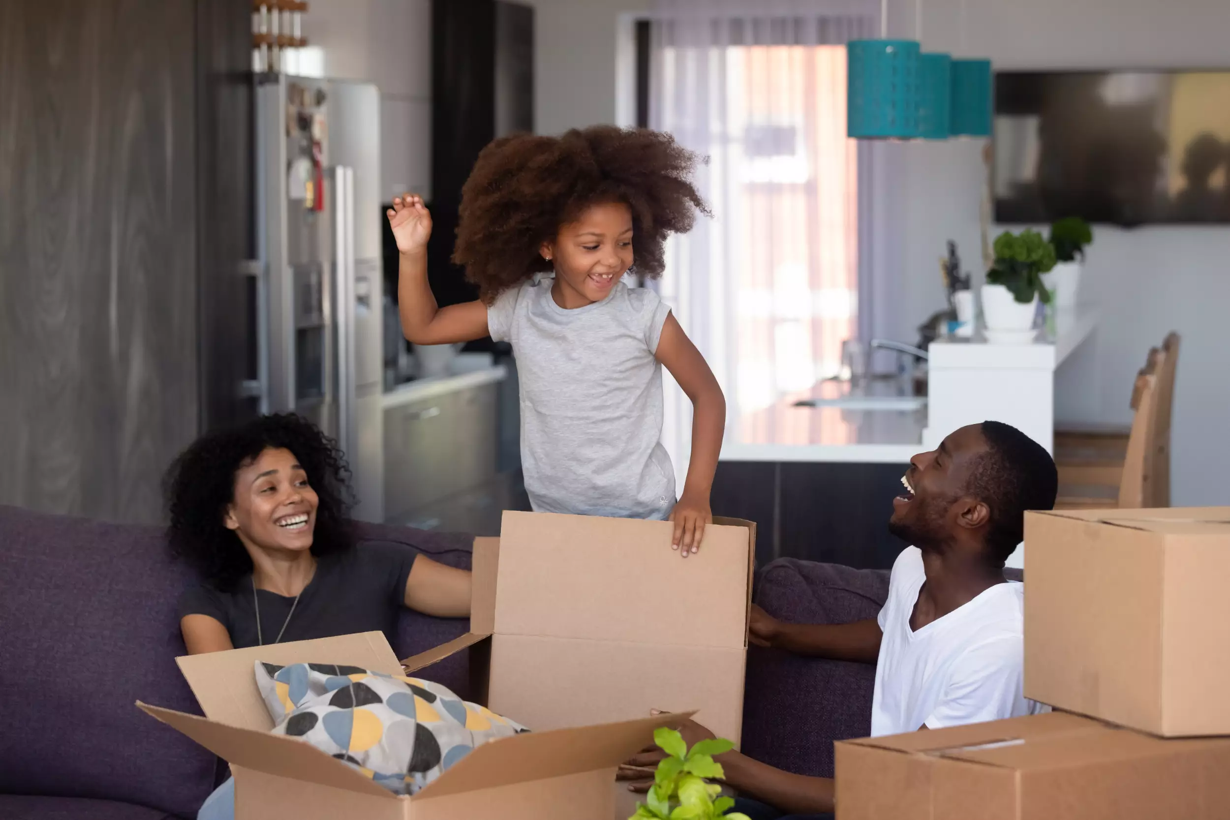 Young child playing in a moving box with parents in new home