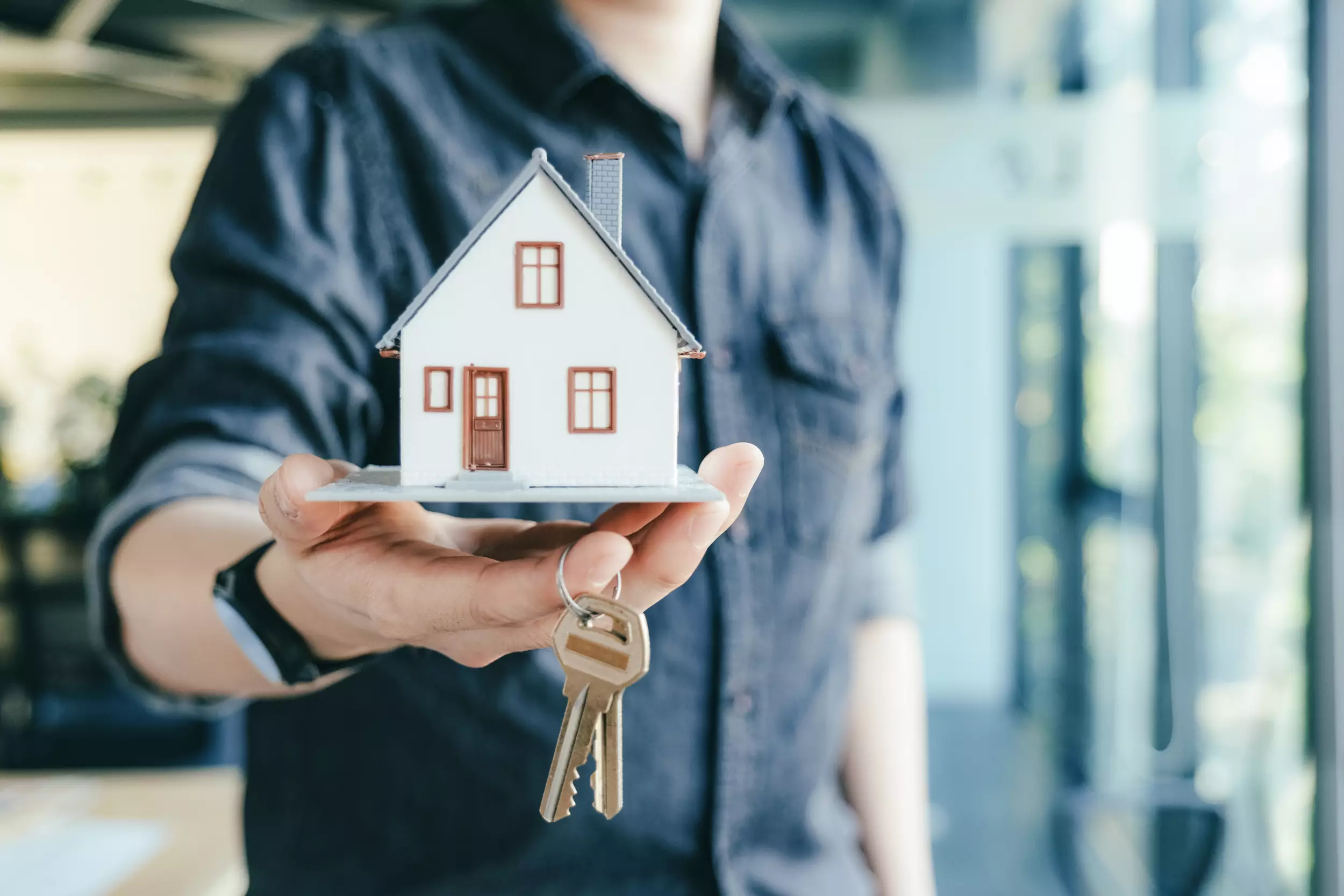 Man holding a model home and house keys